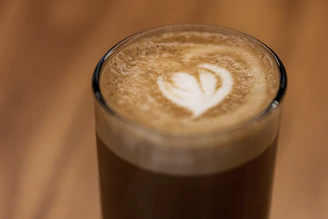 Close-up of a latte art heart in a stone beige cup against the Jeep’s rugged black exterior.