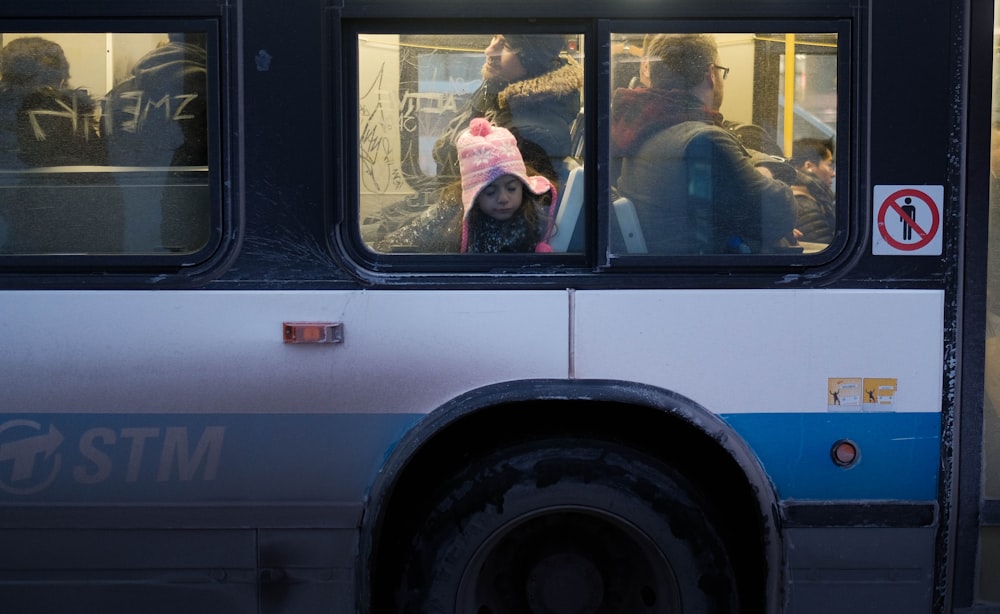 woman in pink dress inside blue and white bus