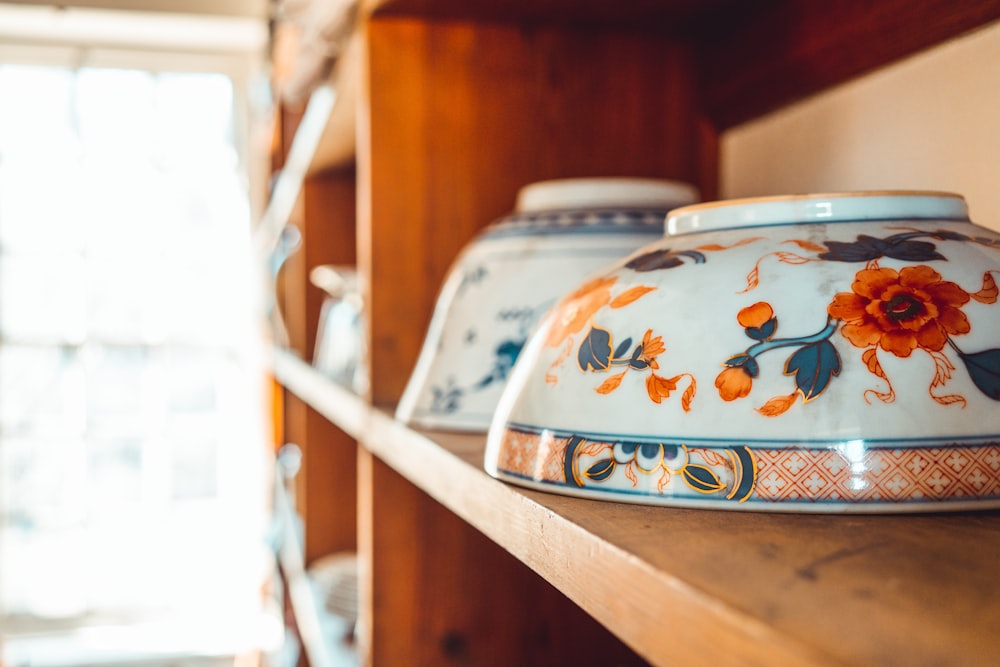 white and blue floral ceramic bowl on brown wooden table