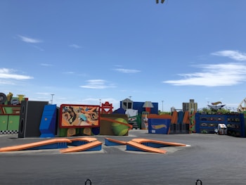 A colorful and dynamic display featuring a large area with various vibrant structures, including oversized props, signs, and a billboard displaying a racing theme. The scene suggests an amusement park or entertainment venue, with structures resembling giant toy car tracks and checkered patterns.