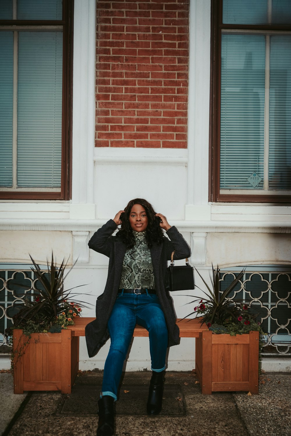 woman in gray long sleeve shirt and blue denim jeans sitting on brown wooden bench