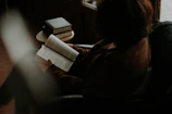 Close-up of a person reading a psychology book in a cozy, softly lit room.