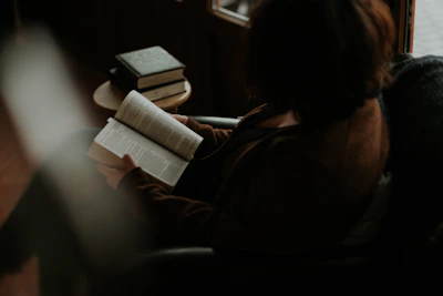 Close-up of a person reading a psychology book in a cozy, softly lit room.