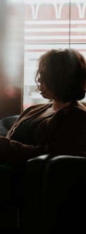 woman in black and brown plaid long sleeve shirt sitting on black sofa