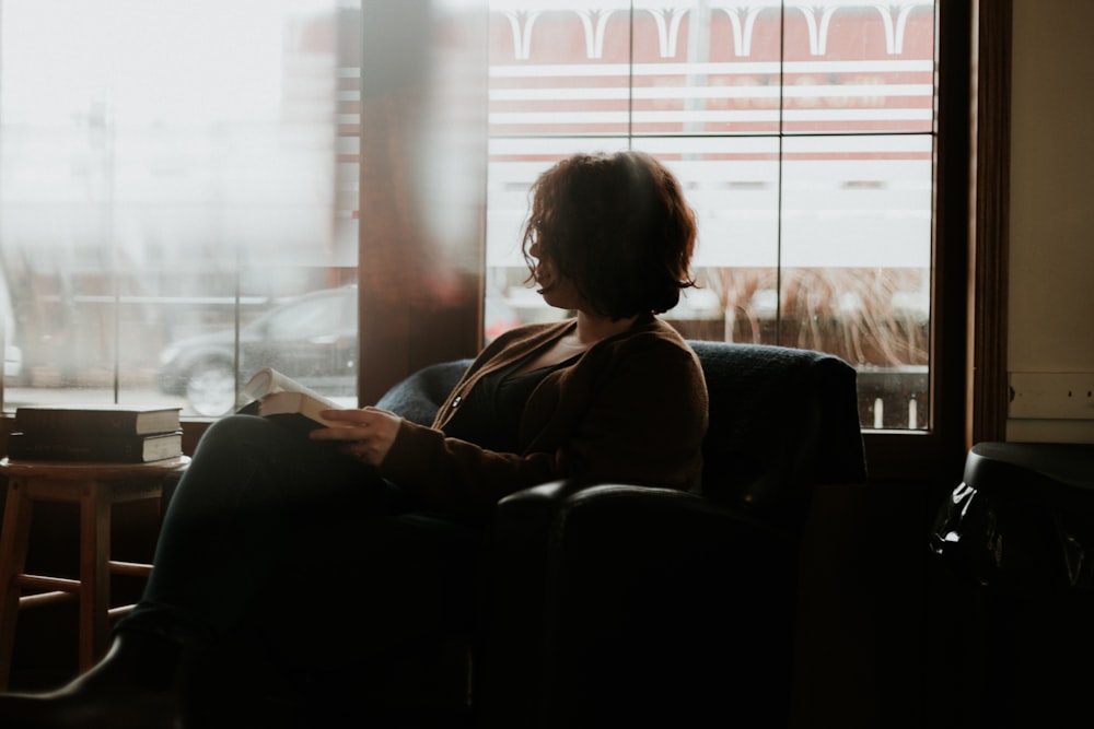 woman in black and brown plaid long sleeve shirt sitting on black sofa