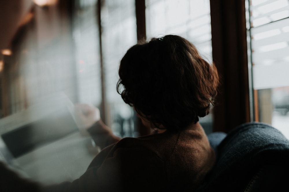 woman in brown shirt looking at the window