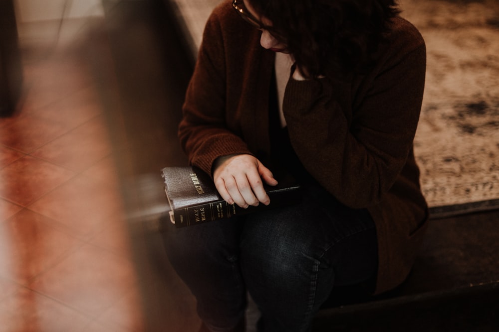 woman in brown sweater and blue denim jeans sitting on couch