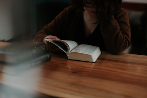 A person reading calmly at home, surrounded by books and notes.