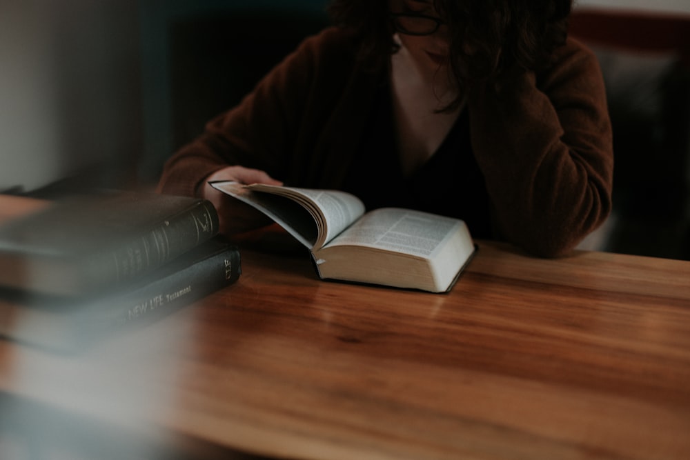 woman reading book on brown wooden table