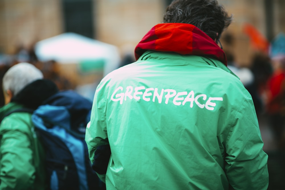 homme en sweat à capuche vert marchant dans la rue pendant la journée