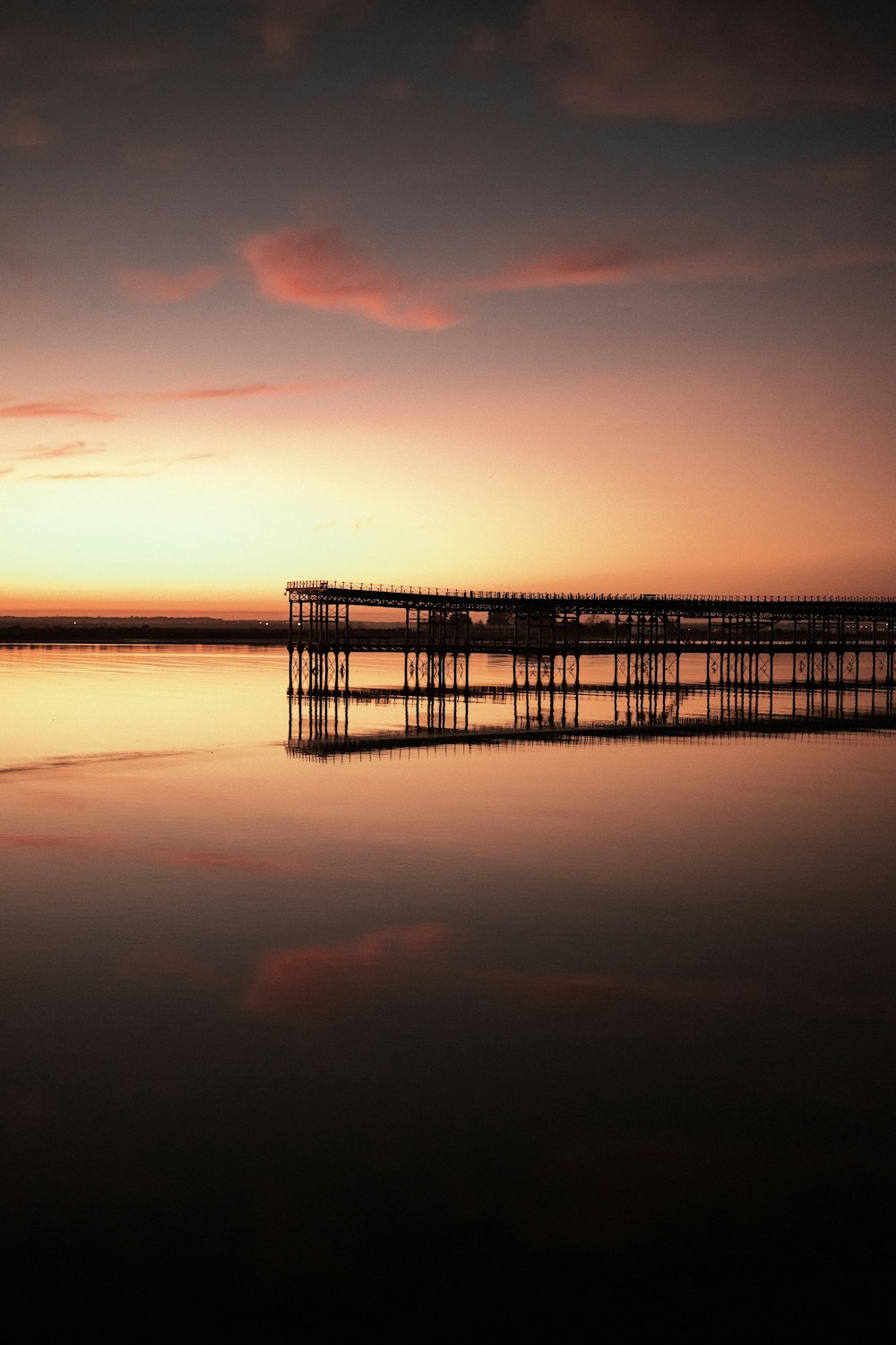 Quai en bois brun sur le plan d’eau au coucher du soleil