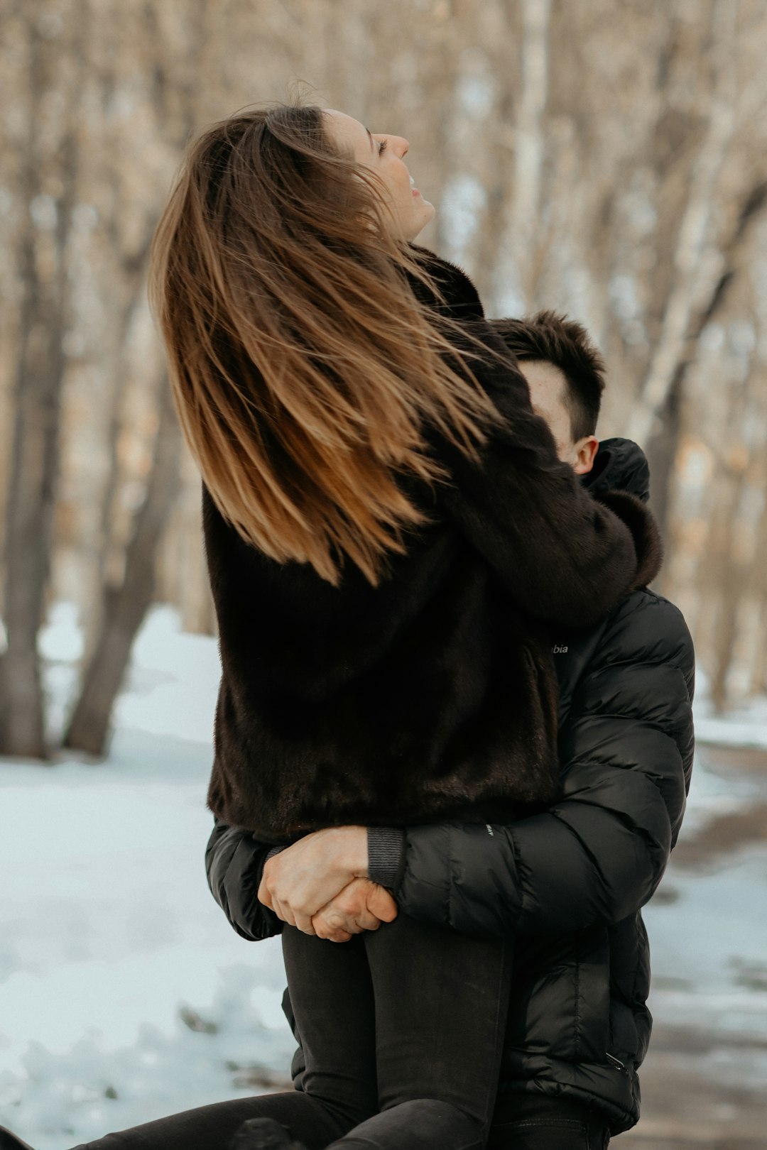 woman in black winter coat standing on snow covered ground during daytime