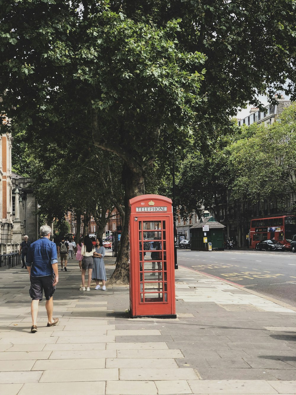 red telephone booth near green trees during daytime