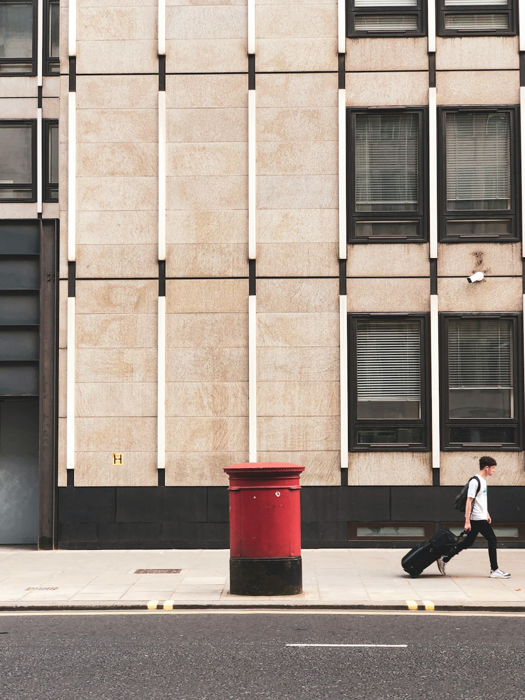 woman in black jacket walking on sidewalk near building during daytime