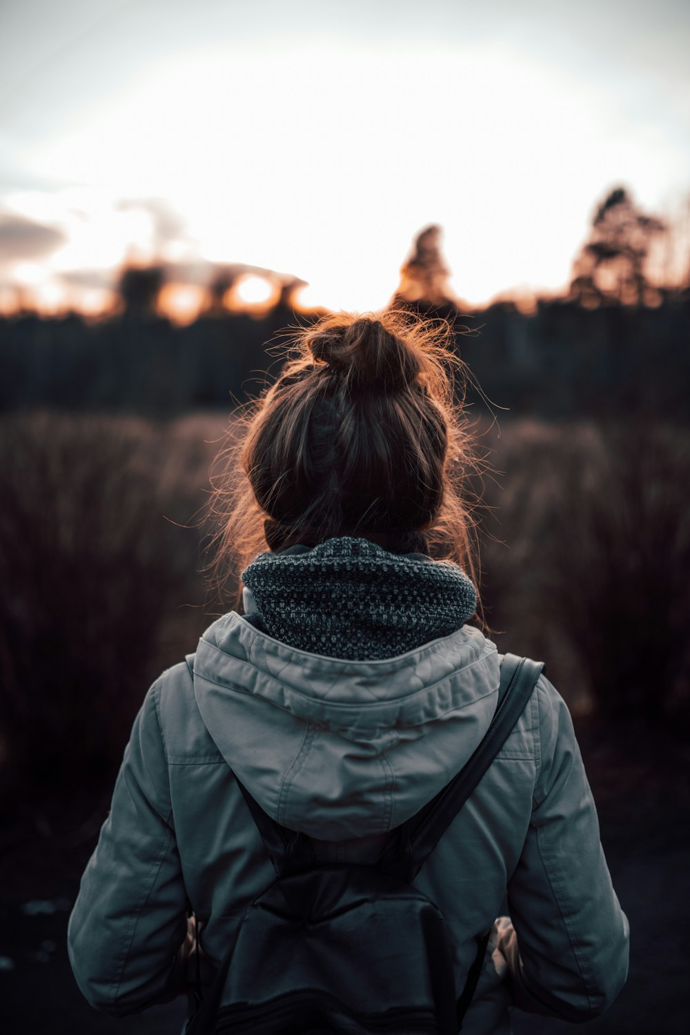 woman in gray and black scarf and green jacket standing on brown field during daytime