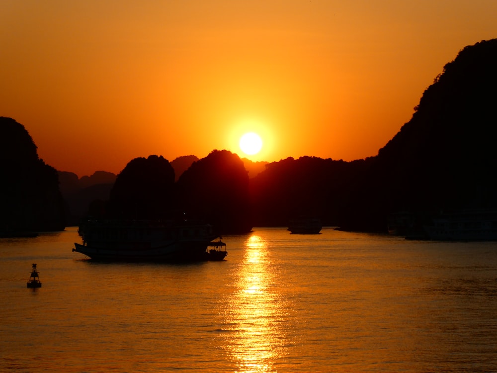 silhouette of boat on sea during sunset