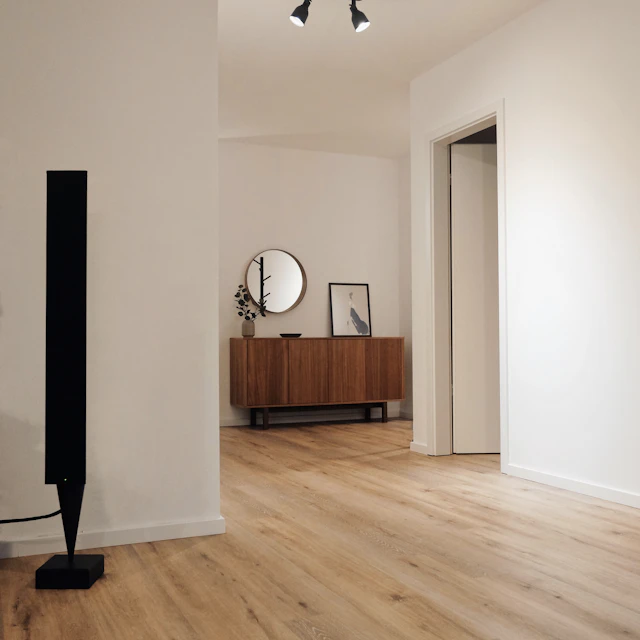Black tower speaker standing next to a white wall
