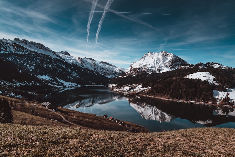 snow covered mountain near lake under blue sky during daytime