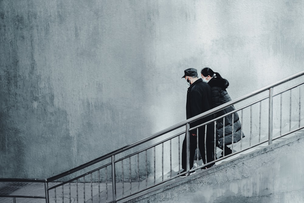 homem em jaqueta preta e boné preto de pé na escada de concreto cinza