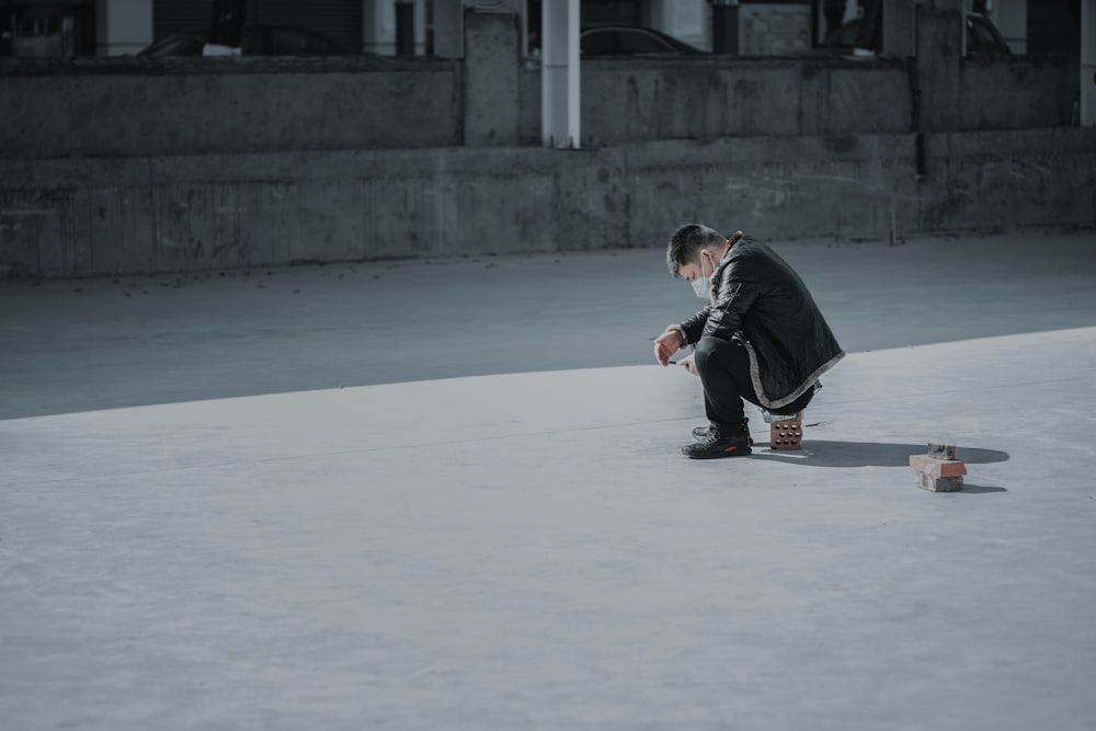 man in black suit and red pants sitting on white floor