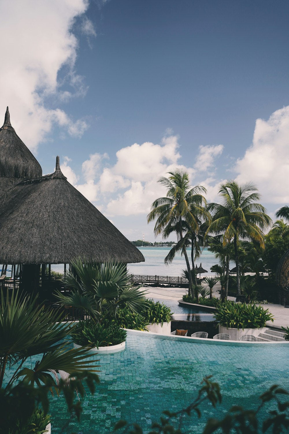 brown nipa hut near palm trees and body of water during daytime