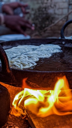 Chef lovingly preparing a traditional baião de dois in a large pan over an open flame.