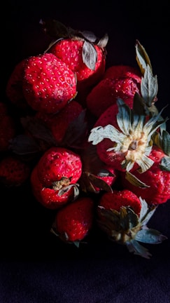 Bright red frozen strawberries scattered on a dark background