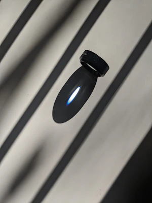 Matte black zeneio smart ring floating against a dark void with electric blue glow.