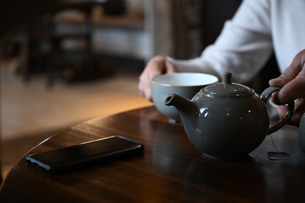 person pouring tea on white ceramic teapot