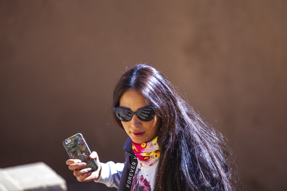 woman in white and pink jacket holding iphone