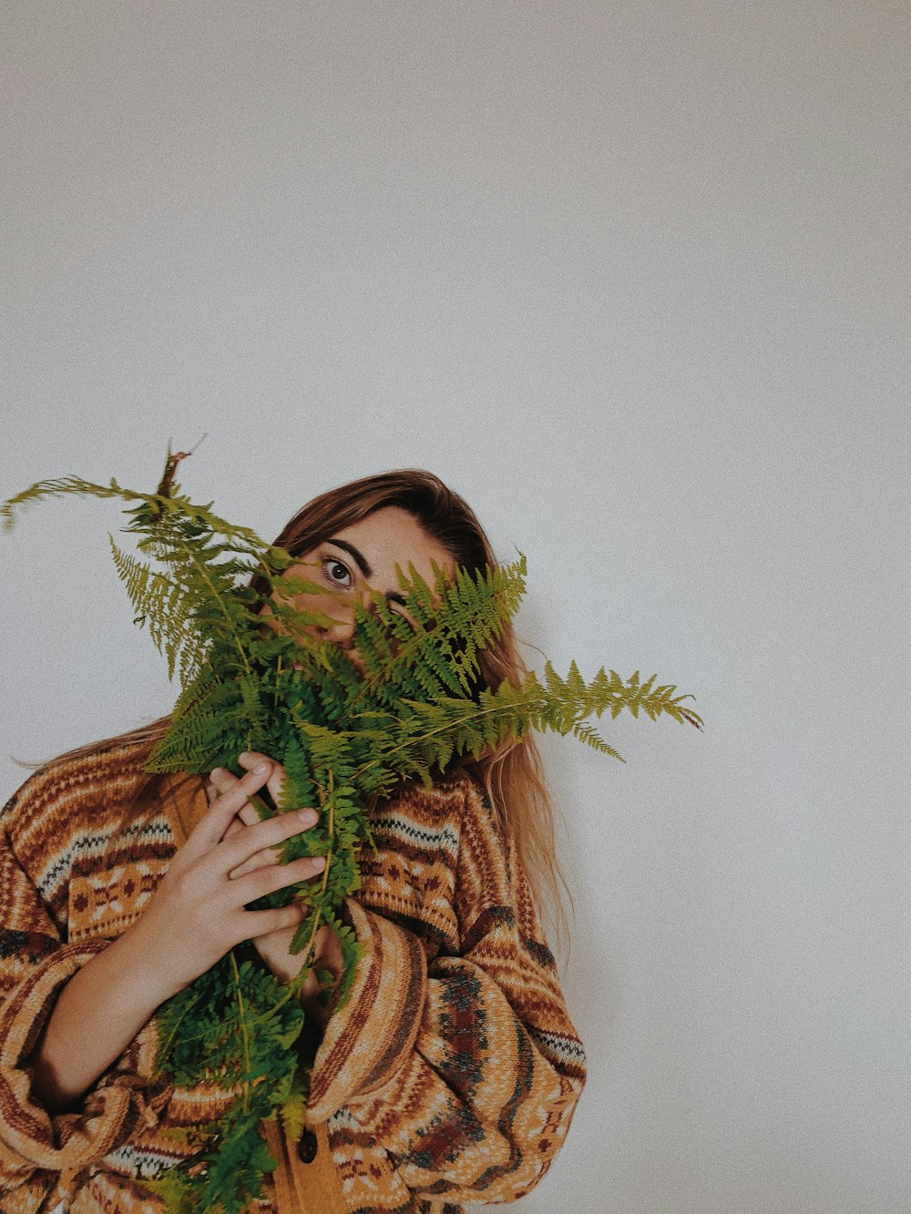 茶色と黒のヒョウ柄のスカーフを着た女性が緑の植物を持っている