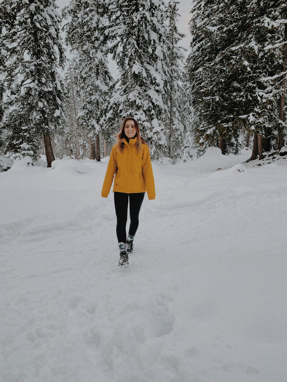 woman in yellow coat standing on snow covered ground