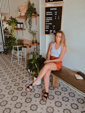 A candid shot of a woman smiling confidently in a trendy, minimalist café setting.