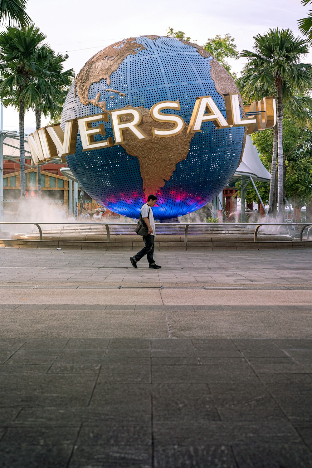 Hombre en chaqueta negra caminando en la acera con globo azul y amarillo en forma de corazón