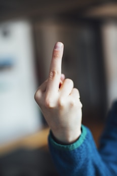 person in blue long sleeve shirt showing right middle finger