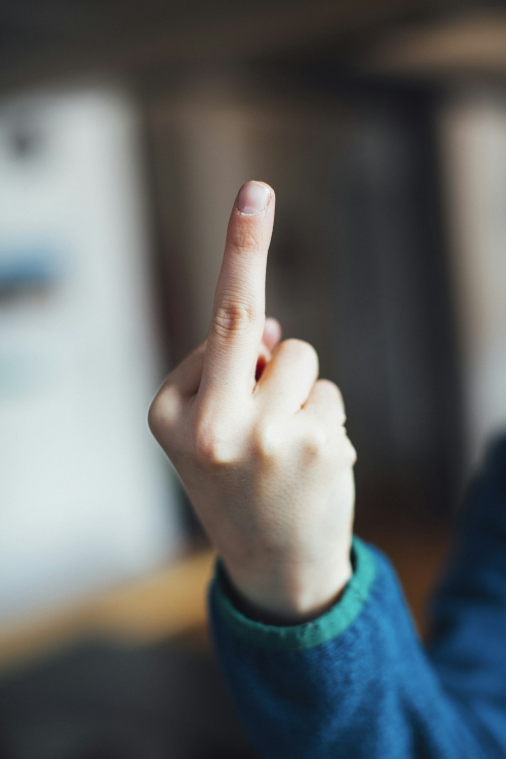 person in blue long sleeve shirt showing right middle finger