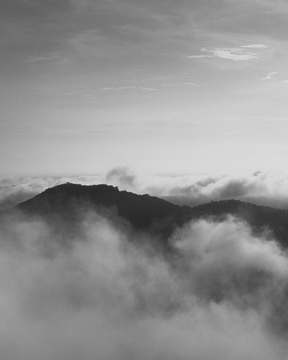 grayscale photo of mountain covered by clouds