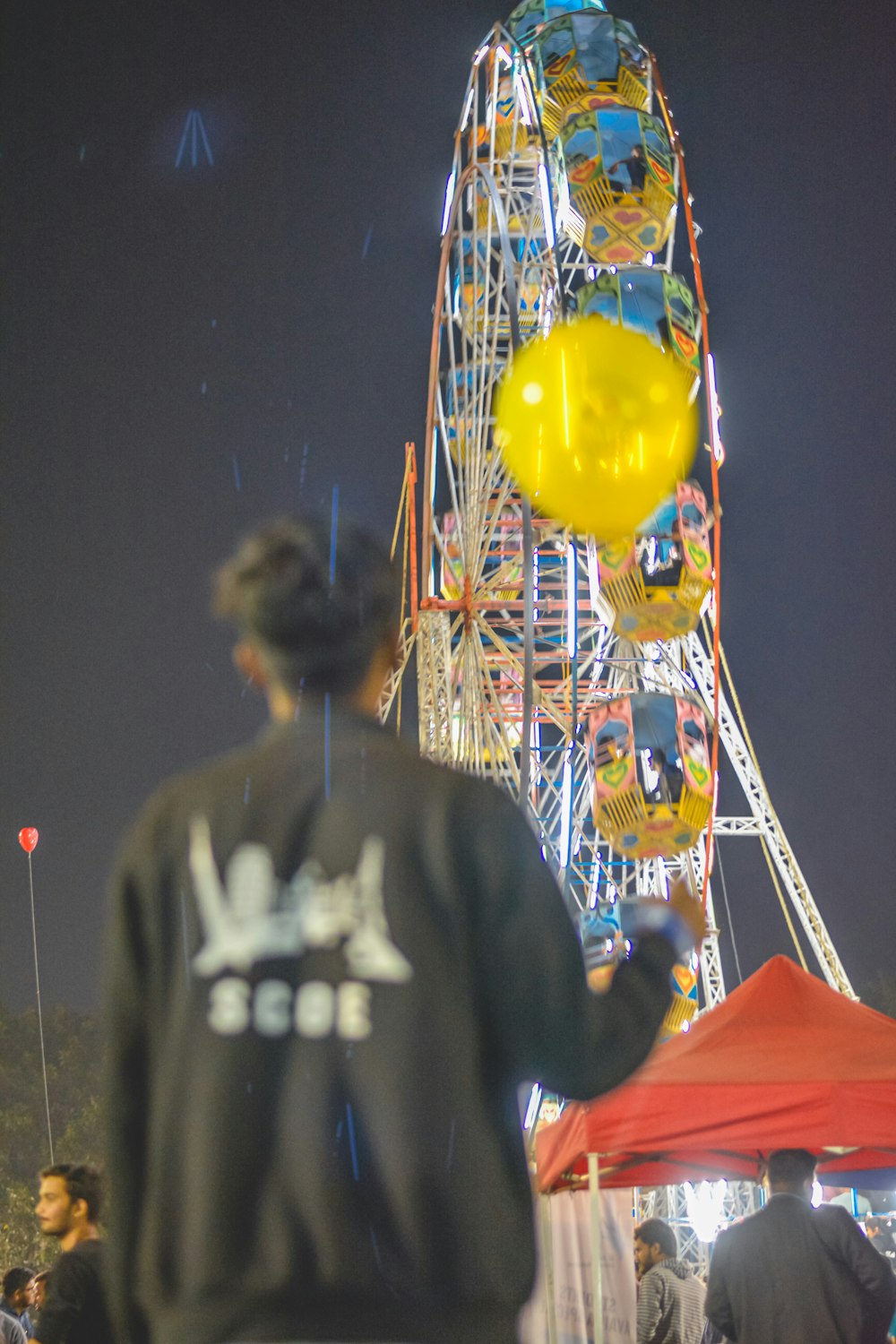 man in gray hoodie standing near yellow and red balloons