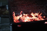 Close-up of the glowing ember-filled interior of a Don Barril smoker grill at dusk.