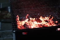 Close-up of bright orange embers glowing inside a charcoal grill.