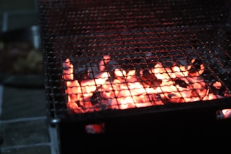 Close-up of glowing charcoal embers in a rustic outdoor grill.