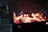 Close-up of glowing charcoal briquettes on a grill with flames.