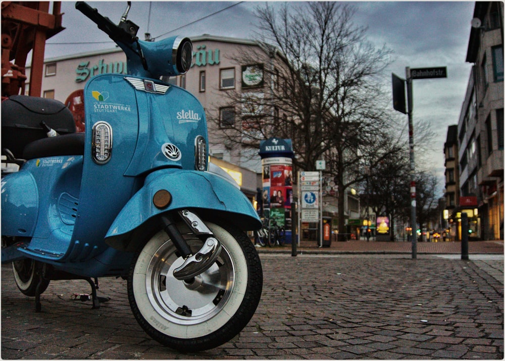 blue and black motorcycle parked on sidewalk near bare trees during daytime