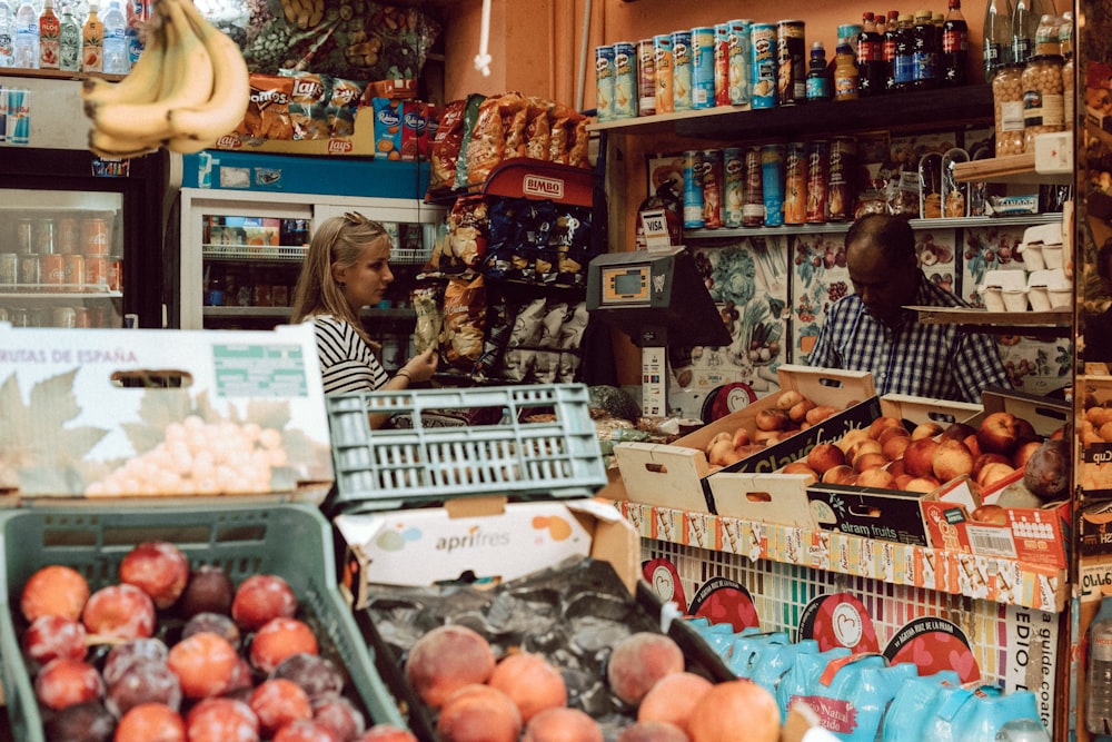 woman in brown long sleeve shirt standing in front of fruit stand
