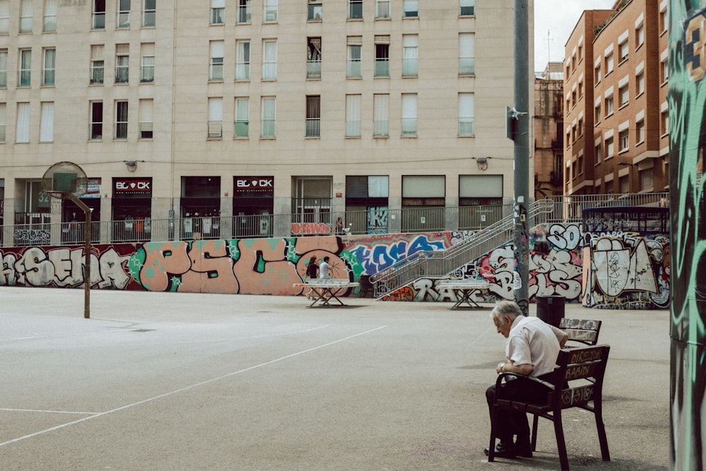 woman in white jacket and black pants sitting on black chair near brown concrete building during