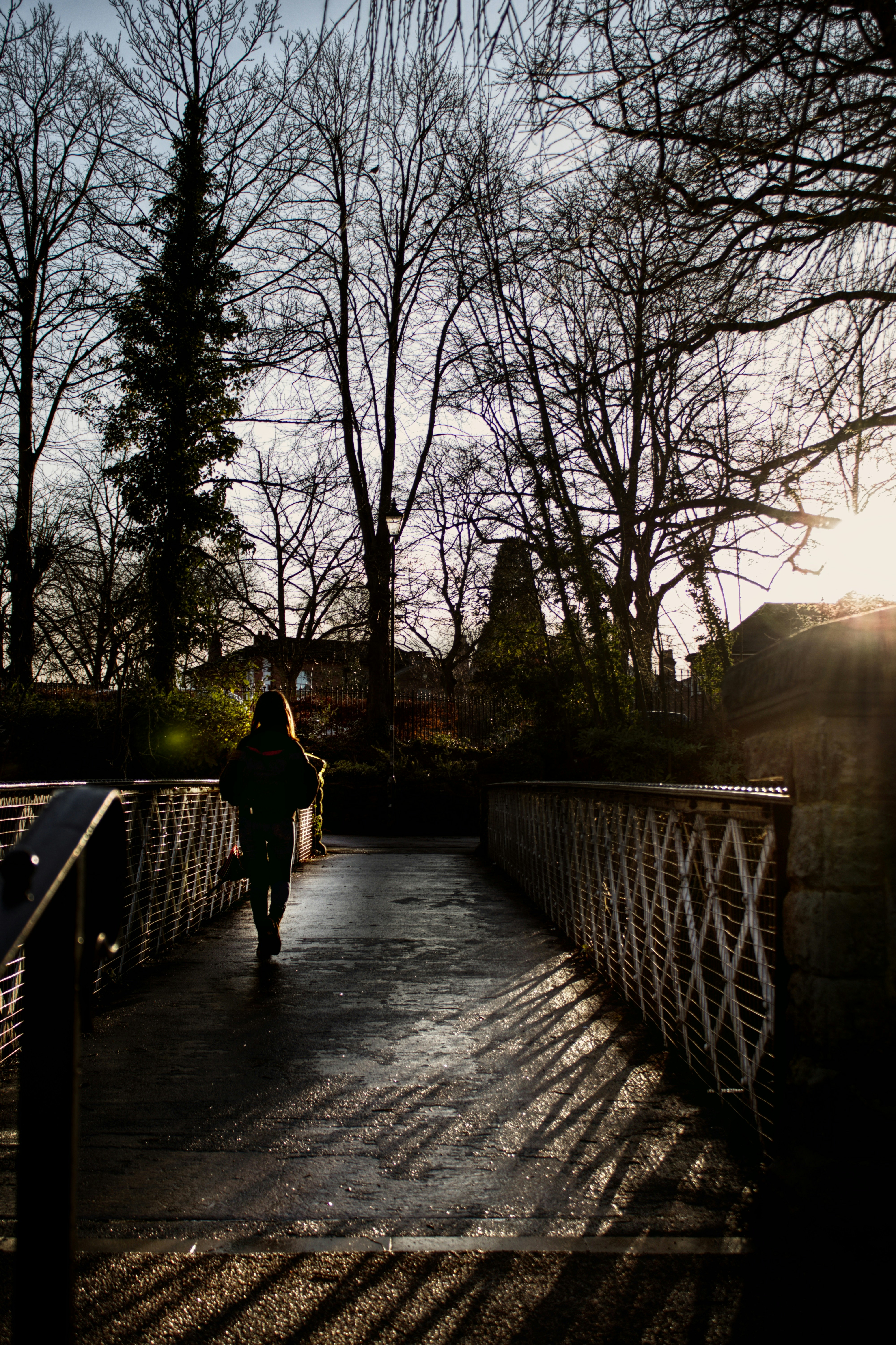 man in black jacket walking on bridge