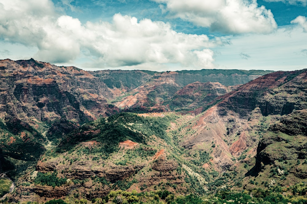 brown and green mountains under white clouds and blue sky during daytime