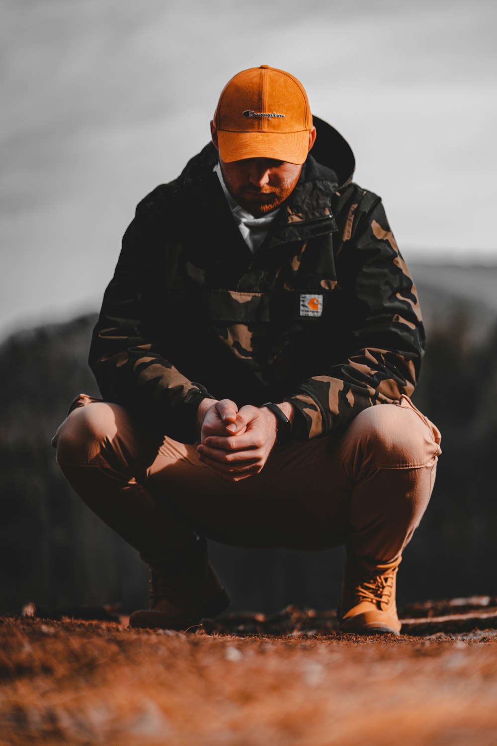 man in black jacket and brown pants sitting on brown rock