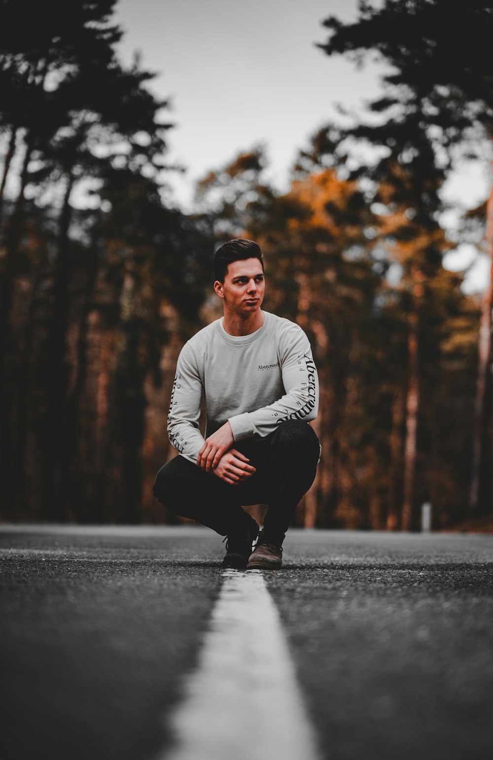 man in white long sleeve shirt and black pants sitting on road during daytime