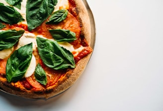 pizza with green leaves on white ceramic plate